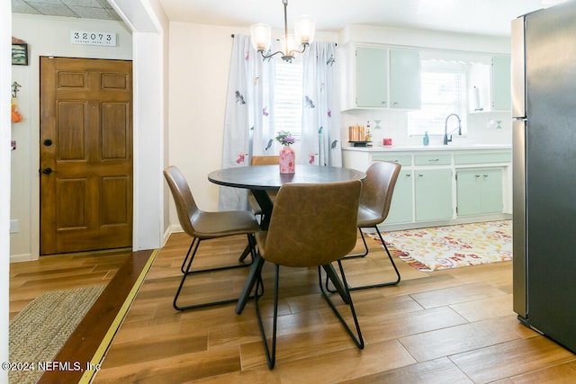 dining space featuring light hardwood / wood-style floors, sink, and an inviting chandelier