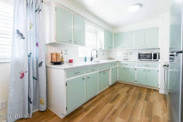 kitchen with light hardwood / wood-style floors, sink, backsplash, and green cabinetry