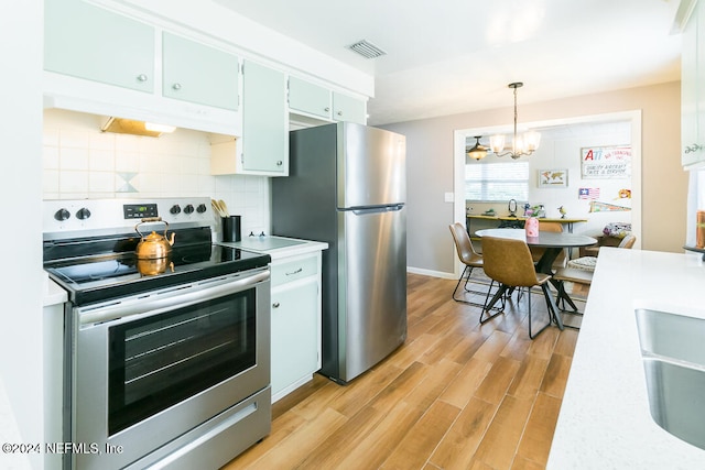 kitchen with decorative backsplash, stainless steel appliances, a chandelier, light hardwood / wood-style floors, and hanging light fixtures