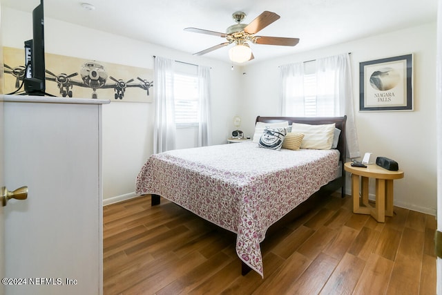 bedroom featuring ceiling fan, dark hardwood / wood-style flooring, and multiple windows