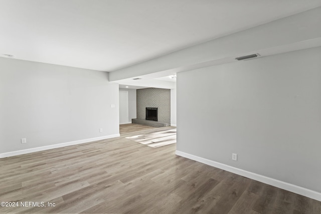 unfurnished living room with light hardwood / wood-style floors and a brick fireplace