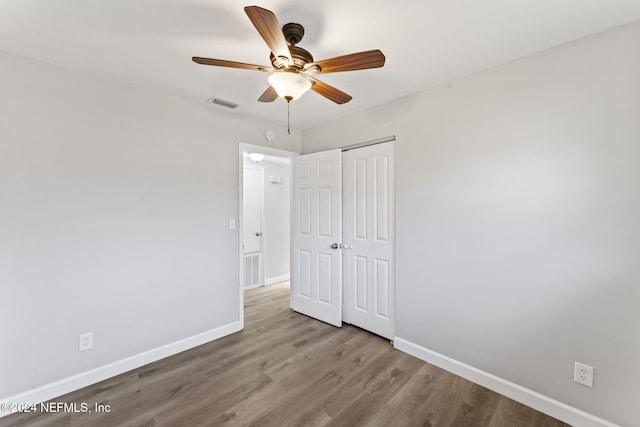 unfurnished bedroom featuring ceiling fan, a closet, and hardwood / wood-style flooring