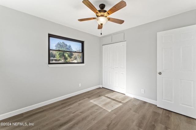 unfurnished bedroom with wood-type flooring, a closet, and ceiling fan