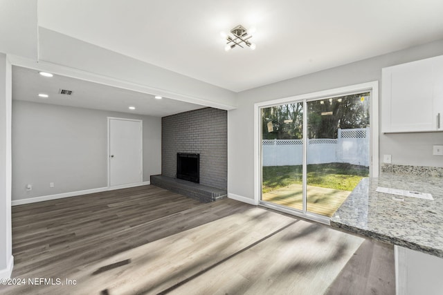 unfurnished living room with dark hardwood / wood-style flooring and a brick fireplace