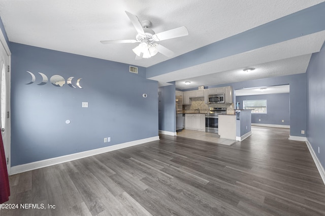 unfurnished living room featuring a textured ceiling, dark hardwood / wood-style floors, and ceiling fan