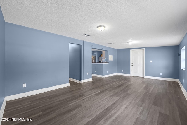 unfurnished living room with dark hardwood / wood-style flooring and a textured ceiling