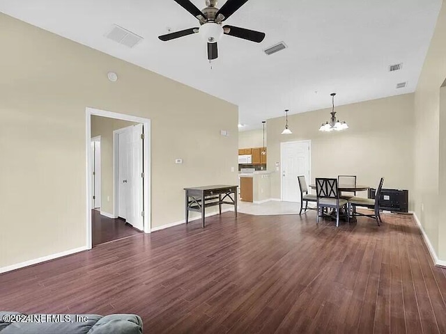 living room with ceiling fan with notable chandelier and dark wood-type flooring