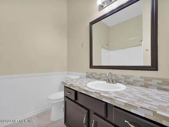 bathroom featuring tile patterned floors, vanity, toilet, and a shower