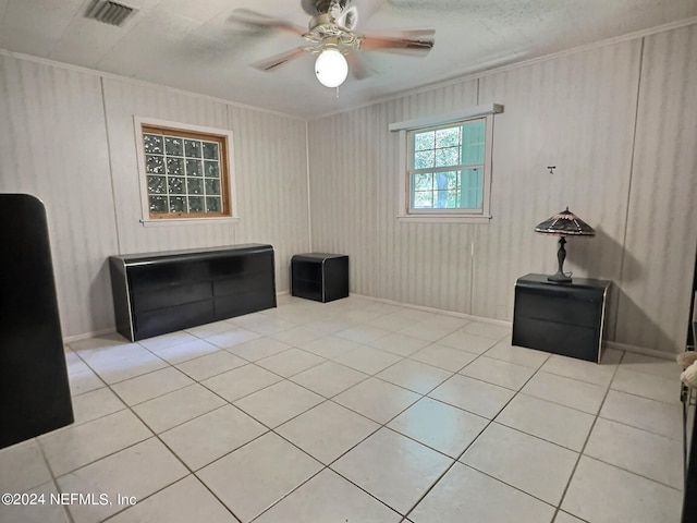 tiled empty room featuring ceiling fan and ornamental molding