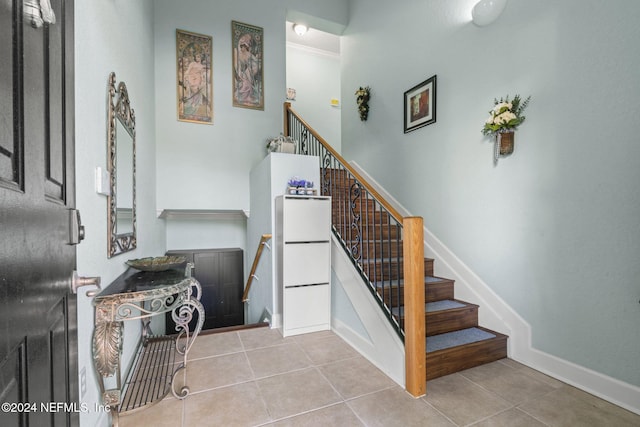 stairs with tile patterned floors and ornamental molding