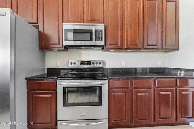 kitchen with appliances with stainless steel finishes and dark stone counters