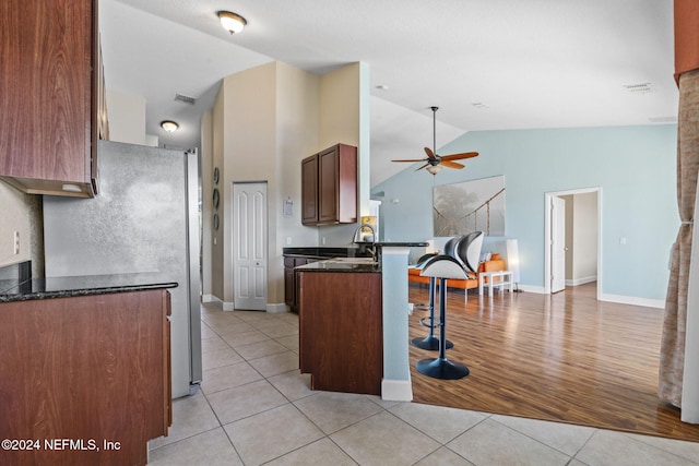 kitchen with kitchen peninsula, a breakfast bar, ceiling fan, sink, and light tile patterned floors