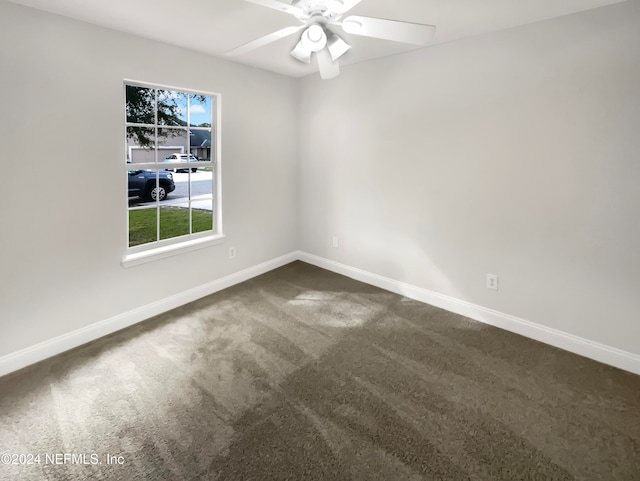 spare room with dark colored carpet and ceiling fan