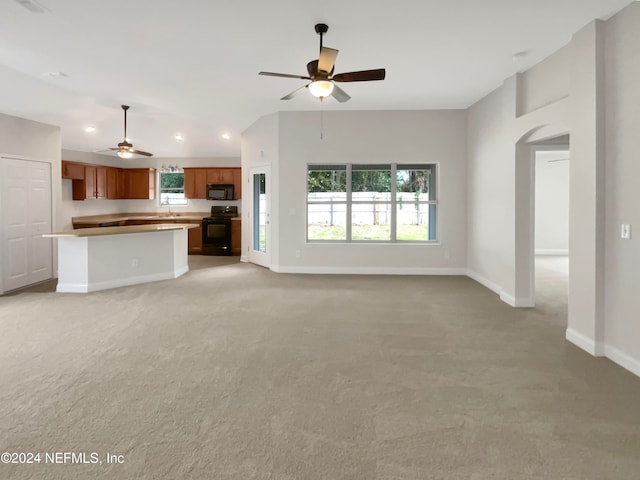 unfurnished living room featuring light carpet, ceiling fan, and sink