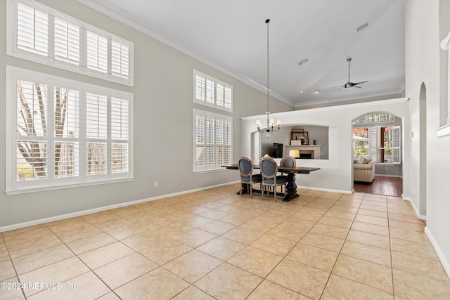 tiled dining space featuring a towering ceiling, a healthy amount of sunlight, and ornamental molding