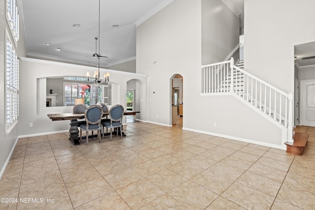 dining area featuring ceiling fan with notable chandelier, light tile patterned floors, a towering ceiling, and crown molding