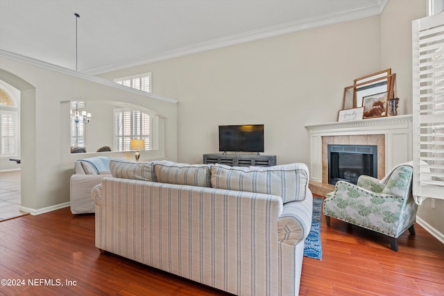 living room with hardwood / wood-style floors, crown molding, a fireplace, and an inviting chandelier