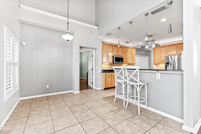 kitchen featuring tasteful backsplash, light tile patterned flooring, decorative light fixtures, and appliances with stainless steel finishes