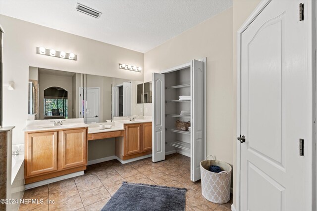 bathroom with tile patterned floors, vanity, and a textured ceiling