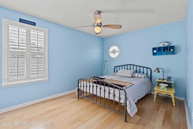 bedroom featuring hardwood / wood-style floors, a textured ceiling, and ceiling fan