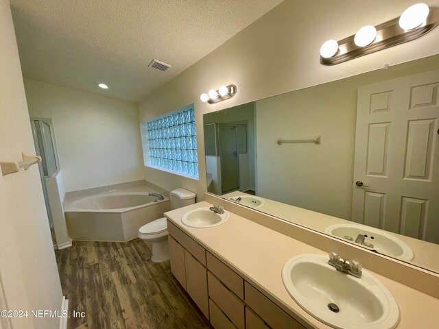 full bathroom featuring vanity, hardwood / wood-style flooring, separate shower and tub, toilet, and a textured ceiling