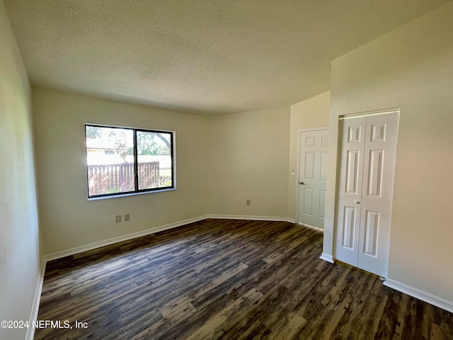 unfurnished room featuring dark hardwood / wood-style floors and a textured ceiling