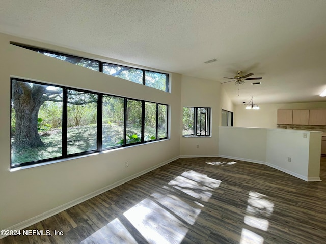 unfurnished room with a textured ceiling, lofted ceiling, dark hardwood / wood-style flooring, and ceiling fan with notable chandelier