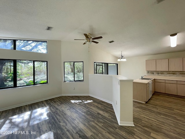 kitchen featuring kitchen peninsula, light brown cabinetry, ceiling fan with notable chandelier, dark wood-type flooring, and lofted ceiling