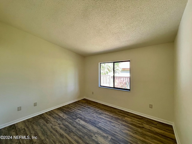 empty room featuring dark wood-type flooring and a textured ceiling