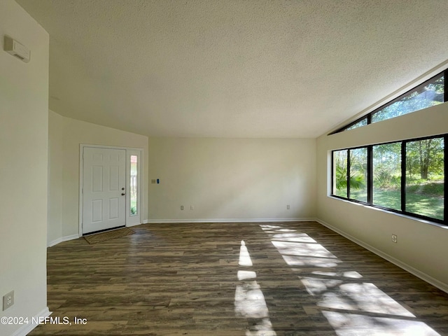 interior space with a textured ceiling, dark hardwood / wood-style floors, and lofted ceiling