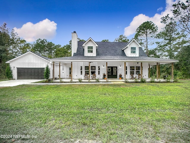 modern farmhouse with covered porch, a front yard, and a garage