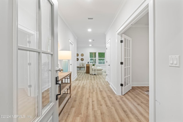 corridor with crown molding, light wood-type flooring, and french doors