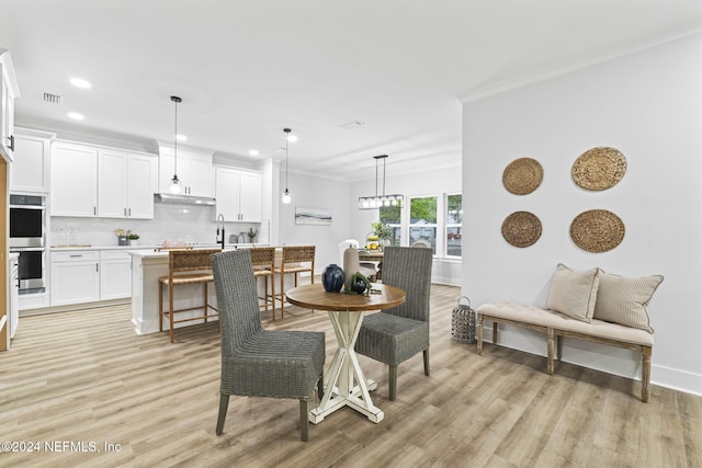 dining area with crown molding and light wood-type flooring