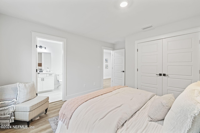 bedroom featuring connected bathroom, a closet, and light wood-type flooring