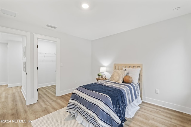 bedroom featuring a walk in closet, a closet, and light wood-type flooring