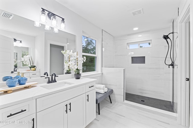 bathroom with tiled shower and vanity