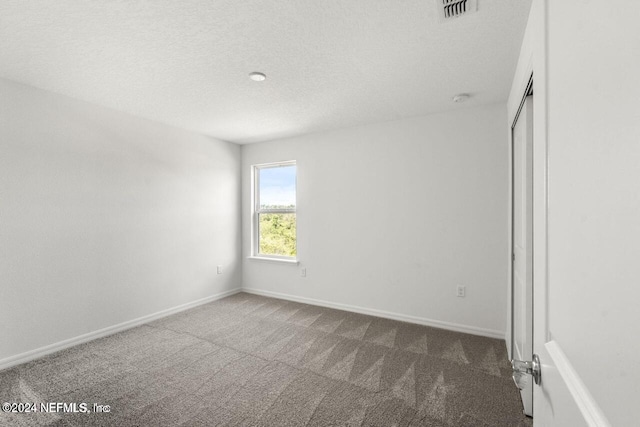 carpeted spare room with a textured ceiling