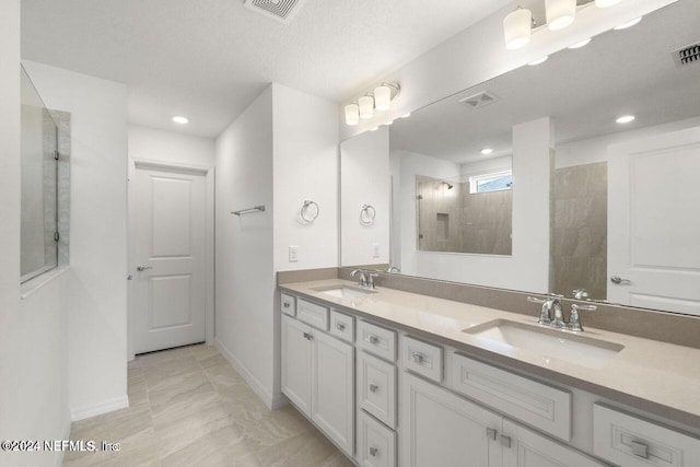 bathroom featuring a tile shower, vanity, and a textured ceiling