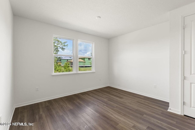 unfurnished room featuring dark wood-type flooring and a textured ceiling