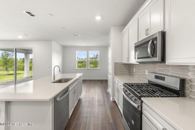 kitchen featuring appliances with stainless steel finishes, a kitchen island with sink, dark wood-type flooring, sink, and white cabinets