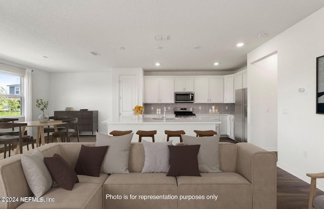 living room featuring sink, wood-type flooring, and a textured ceiling