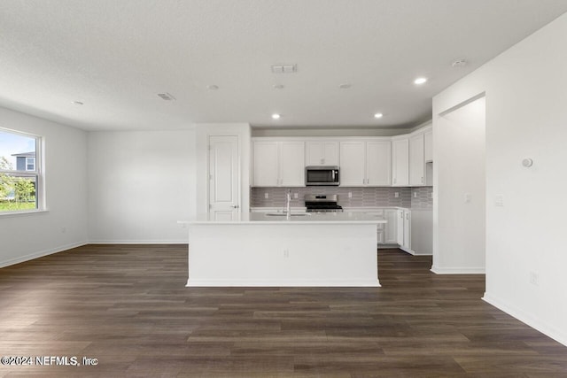 kitchen with white cabinets, stainless steel appliances, a kitchen island with sink, and dark hardwood / wood-style floors