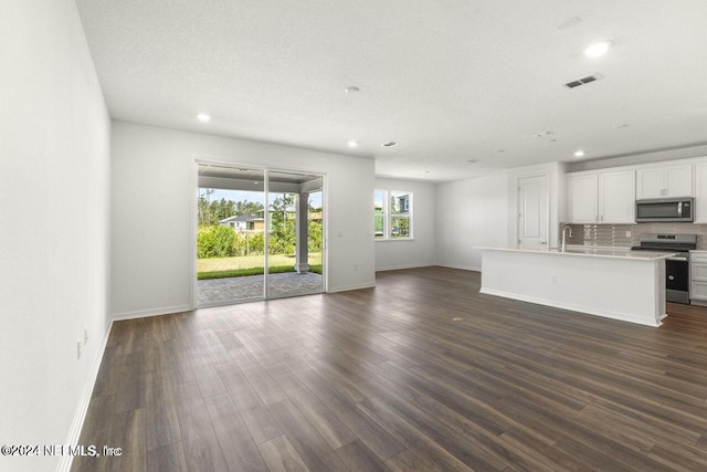 unfurnished living room featuring a textured ceiling, dark wood-type flooring, and sink