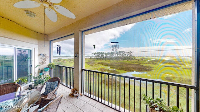 sunroom / solarium featuring ceiling fan and a water view