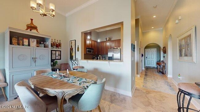 dining room with a notable chandelier, crown molding, and a high ceiling