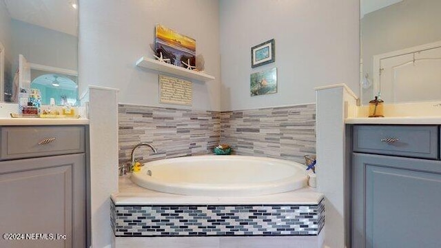 bathroom featuring tiled tub and vanity