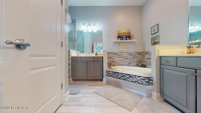 bathroom with vanity, tile patterned floors, and tiled bath