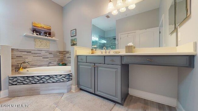 bathroom with vanity and tiled bath