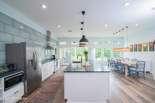 kitchen featuring white cabinetry, a kitchen island with sink, and hanging light fixtures