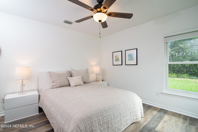 bedroom featuring dark hardwood / wood-style flooring, multiple windows, and ceiling fan